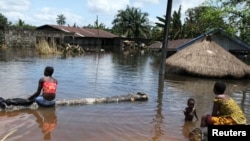 尼日利亞帕坦尼的居民10月15日坐在一棟被水淹的樓房的前面。