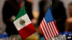 FILE - Miniature national flags representing Mexico and the United States stand side by side during trade discussions in Mexico City, July 29, 2014.