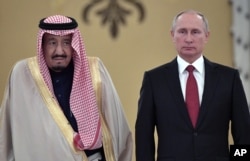 FILE - In this Oct. 5, 2017 file photo, Russian President Vladimir Putin, right, and Saudi Arabia's King Salman pose for a photo during a welcoming ceremony in Moscow.