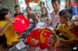 FILE - People gather to buy merchandise with pictures of Myanmar opposition leader Aung San Suu Kyi at a shop run by her National League of Democracy party in Yangon, Myanmar, Nov. 10, 2015.