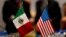FILE - Miniature national flags representing Mexico and the United States stand side by side during trade discussions in Mexico City, July 29, 2014.