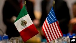 FILE - Miniature national flags representing Mexico and the United States stand side by side during trade discussions in Mexico City, July 29, 2014.