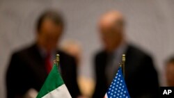 FILE - Miniature national flags representing Mexico and the United States stand side by side during trade discussions in Mexico City, July 29, 2014.