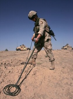 FILE - A US Army soldier searches for explosive devices on the side of a road in Baghdad Aug. 5, 2005.