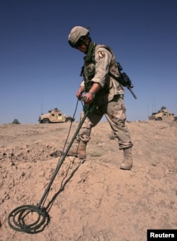 FILE - A US Army soldier searches for explosive devices on the side of a road in Baghdad Aug. 5, 2005.