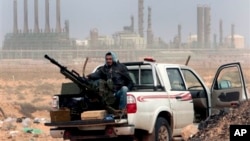 In this March 5, 2011 file photo, an anti-government rebel sits with an anti-aircraft weapon in front an oil refinery, after the capture of the oil town of Ras Lanouf, eastern Libya. The official Libyan news agency said Sunday, April 6, 2014 that the country's main militia in the east has agreed to hand back control of four oil terminals it captured and shut down last summer in its demand for a share in oil revenues. The shutdown has cost Libya millions of dollars. (AP Photo/Hussein Malla, File)
