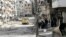 Free Syrian Army fighters walk along a street piled with damaged building as they head toward the frontline in Aleppo's Salaheddine district, April 8, 2013.