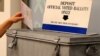 FILE - A ballot is placed into a locked ballot box by a poll worker as people line-up to vote early at the San Diego County Elections Office in San Diego, California, Nov. 7, 2016. 