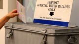 A ballot is placed into a locked ballot box by a poll worker as people line-up to vote early at the San Diego County Elections Office in San Diego, California, US, Nov. 7, 2016. 