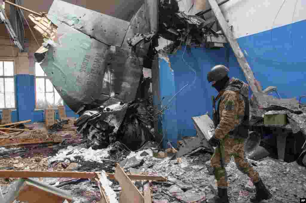 A Ukrainian serviceman walks past the vertical tail fin of a Russian Su-34 bomber lying in a damaged building in Kharkiv, March 8, 2022.