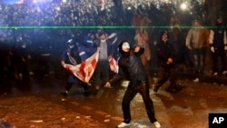 Un manifestante lanza un objeto hacia la policía durante una manifestación contra la decisión de los gobiernos de suspender las negociaciones para unirse a la Unión Europea durante cuatro años, frente al edificio del parlamento en Tbilisi, Georgia, el 1 de diciembre de 2024. AP