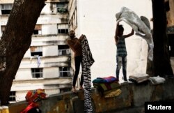 Rodrigo (left), 26, and Wam, 24, who are among members of lesbian, gay, bisexual and transgender (LGBT) community, that have been invited to live in a building that the roofless movement has occupied, shake blankets, in downtown Sao Paulo, Brazil, Nov. 8, 2016.