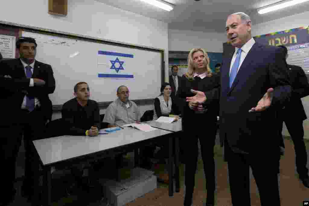 Perdana Menteri Israel Benjamin Netanyahu didampingi istrinya Sara berbicara dengan media setelah memberikan suara dalam pemilu di Yerusalem (17/3). (AP/Sebastian Scheiner, Pool)