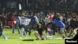 Suporter Arema FC memasuki lapangan usai tim yang mereka dukung kalah dari Persebaya usai pertandingan sepak bola liga BRI Liga 1 di Stadion Kanjuruhan, Malang, Jawa Timur, 2 Oktober 2022. (Foto: Antara/Ari Bowo Sucipto via REUTERS)