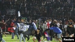 Arema FC supporters enter the field after the team they support lost to Persebaya after a football match at Kanjuruhan Stadium