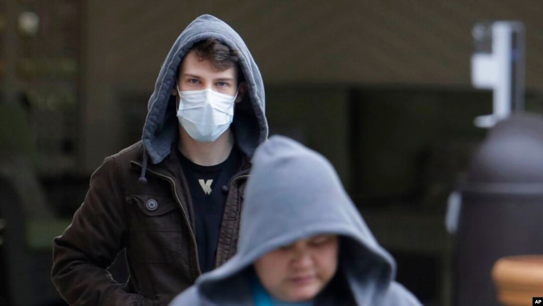 一个戴着口罩的男子从华盛顿州柯克兰市生命护理中心的入口离开（2020年3月3日）。