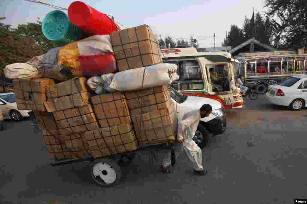 Seorang pedagang mengangkut barang-barang dagangan dengan keretanya di dekat pasar di Karachi, Pakistan.