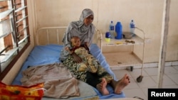 FILE - A Somali refugee holds a toddler at a hospital in the Dadaab refugee camp, Kenya, Dec. 19, 2017.