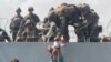 A baby is handed to U.S. soldiers over the perimeter wall of the airport for it to be evacuated, in Kabul, Afghanistan, Aug. 19, 2021, in this still image taken from video obtained from social media. 