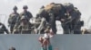 A baby is handed to U.S. soldiers over the perimeter wall of the airport for it to be evacuated, in Kabul, Afghanistan, Aug. 19, 2021, in this still image taken from video obtained from social media. 