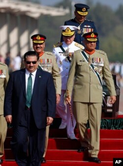 FILE - Pakistan Defense Minister Khurram Dastgir, left, with Army Chief Qamar Javed Bajwa, right, and other officers arrive for a military parade in Islamabad, March 23, 2018.
