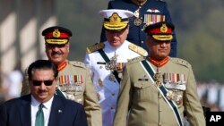 FILE - Pakistan Defense Minister Khurram Dastgir, left, with Army Chief Qamar Javed Bajwa, right, and other officers arrive for a military parade in Islamabad, March 23, 2018. 
