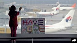 Una niña junto a un cartel que lee "Ten fe" en el aeropuerto de Kuala Lumpur, donde se originó el vuelo de Malasya Arilines extraviado el sábado.