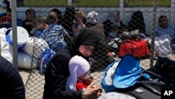 FILE - A Syrian woman and child living in Turkey wait to cross into Syria at the Oncupinar border crossing, near the town of Kilis, Turkey, June 13, 2017.