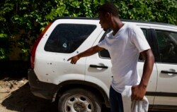 A bystander points to a vehicle, perforated with bullets holes, parked outside the residence of Haitian President Jovenel Moise, in Port-au-Prince, Haiti, Wednesday, July 7, 2021.