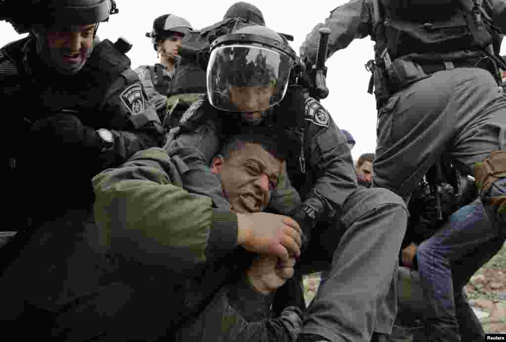 Israeli border policemen detain a Palestinian man as they clear a protest on the land that Palestinians said was confiscated by Israel for Jewish settlements, near the West Bank town of Abu Dis near Jerusalem.