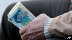 An Iranian street money changer holds Iranian banknotes with a portrait of late revolutionary founder Ayatollah Khomeini.