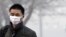 A man wears a mask as he walks to cross a street shrouded by haze in Beijing, China, Jan. 10, 2012.