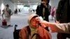 Seorang petugas memeriksa temperatur seorang penumpang setibanya di bandara Soekarno-Hatta, Rabu (22/1). (AP Photo/Tatan Syuflana)