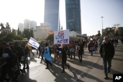 People march as they protest against Israeli police and demand the appointment of an investigating judge to probe the killing of Yehuda Biadga, a mentally ill Ethiopian-Israeli, by Israeli police, in Tel Aviv, Israel, Wednesday, Jan. 30, 2019.