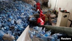 FILE—Workers load clear plastic bottles in to a crushing machine at the Dawn to Glory PET flakes export company in industrial area of Nairobi, Kenya, November 16, 2023.