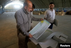 A worker from the Iraqi Independent High Electoral Commission checks voting materials at a warehouse in Najaf, Iraq, April 18, 2018.