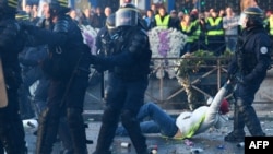 A policeman evacuates a demonstrator in Quimper, western France, during a day of nationwide protest called "yellow vest" (Gilets Jaunes in French) movement to protest against high fuel prices, Nov. 17, 2018.