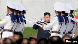 Pemimpin Korea Utara Kim Jong-un memberikan penghormatan kepada para petugas yang berpawai melintasi tribun kehormatan di acara peresmian Taman Makam Pahlawan Korea Utara di Pyongyang (25/7).