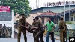 Para narapidana Sri Lanka berteriak-teriak dari atas atap bangunan penjara, saat petugas mengangkat korban yang terluka keluar dari penjara Welikada, Kolombo, Sri Lanka (9/11). 