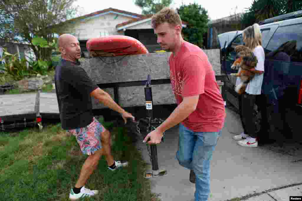 Scott Pepperman (L), and his son Cobi move a trailer while preparing to evacuate from their home ahead of the arrival of Hurricane Milton in New Port Richey, Florida, Oct. 8, 2024.