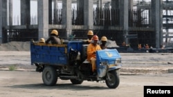 FILE - Workers ride in a vehicle at the construction site of the Dangote oil refinery in Ibeju Lekki district, on the outskirts of Lagos, Nigeria, Aug. 7, 2019. 