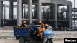 FILE - Workers ride in a vehicle at the construction site of the Dangote oil refinery in Ibeju Lekki district, on the outskirts of Lagos, Nigeria, Aug. 7, 2019. 