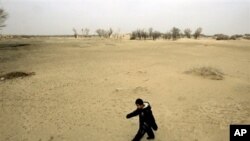 A child walks across a sand dune in Gansu province, China, where desertification threatens for force farmers from their land.