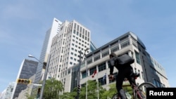 FILE - A man cycles past the International Civil Aviation Organization headquarters building in Montreal, Quebec, June 15, 2017.