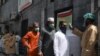 A man checks the body temperature of worshippers arriving for Friday prayers at a mosque in Lahore, Pakistan, May 1, 2020.