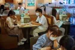 People sit in a restaurant using plexiglass separators to protect customers from coronavirus (COVID-19) disease in the Shibuya area of Tokyo, Japan, July 29, 2021.