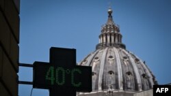 (FILES) This photograph taken on July 19, 2023, shows a pharmacy's sign indicating the current outside temperature is 40 degrees celsius, with the dome of Saint Peter Basilica in the background, in Rome amid a heatwave in Italy.