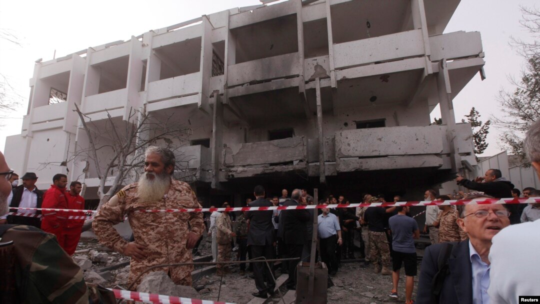 Warga berdiri diantara reruntuhan gedung di luar Kedutaan Besar Perancis di ibukota Libya, Tripoli, menyusul serangan bom di lokasi tersebut (23/4).