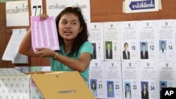 An election worker shows a ballot during ballot counting at a polling station in Bangkok, Thailand, on Sunday, July 3, 2011