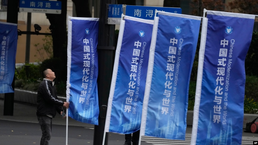 一名工人在上海街頭整理豎立的宣傳旗幟：“中國式現代化與世界”。 （2023年4月21日）